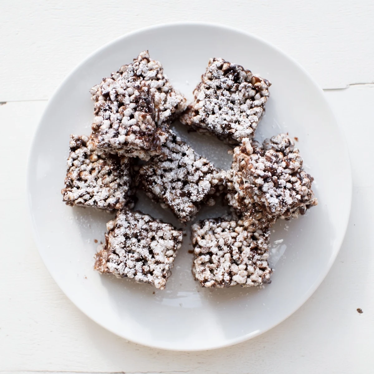 Homemade Muddy Buddy Rice Krispies cereal bars with melted chocolate drizzle and powdered sugar dusting