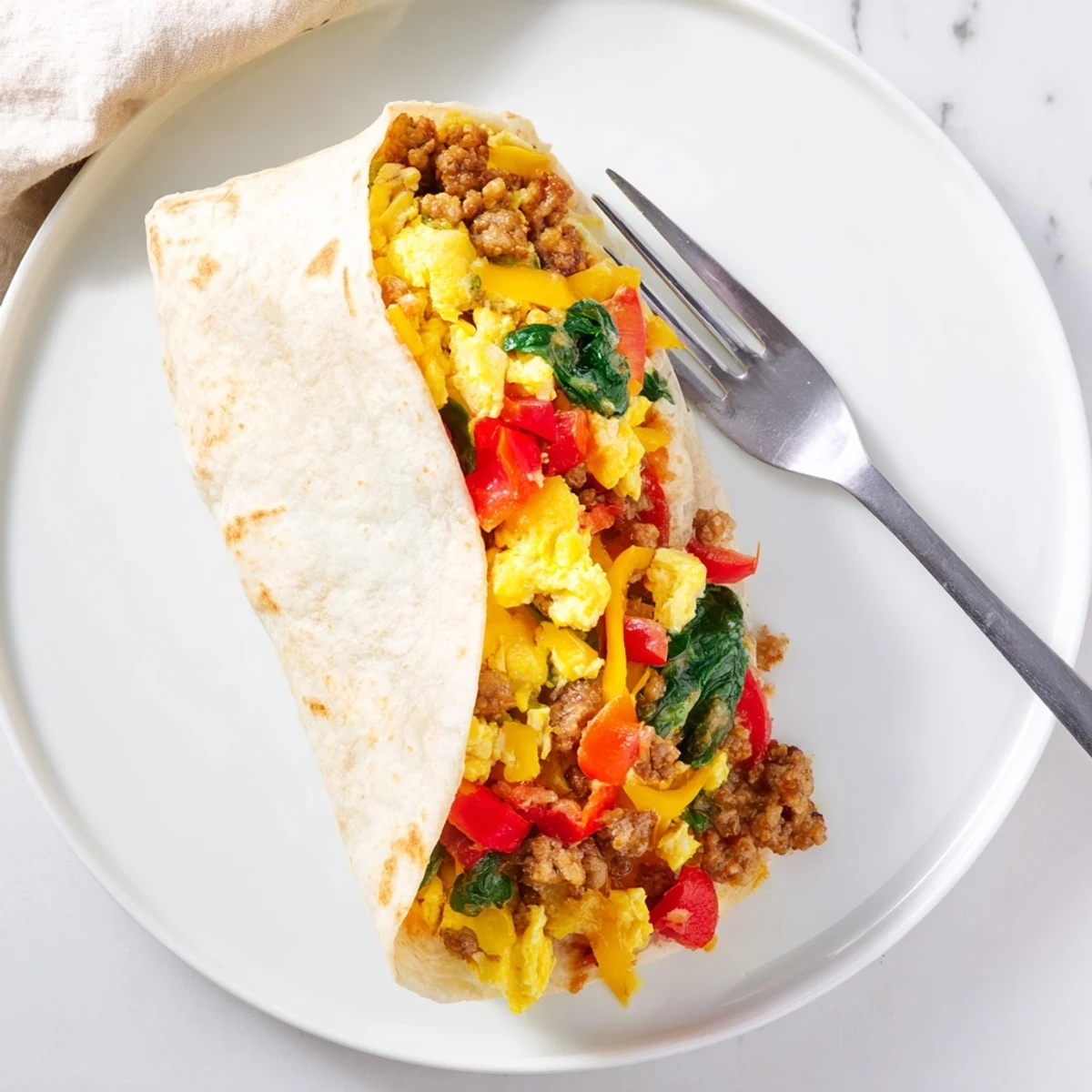 Handheld make-ahead breakfast burritos filled with scrambled eggs, peppers, onions, and cheddar cheese