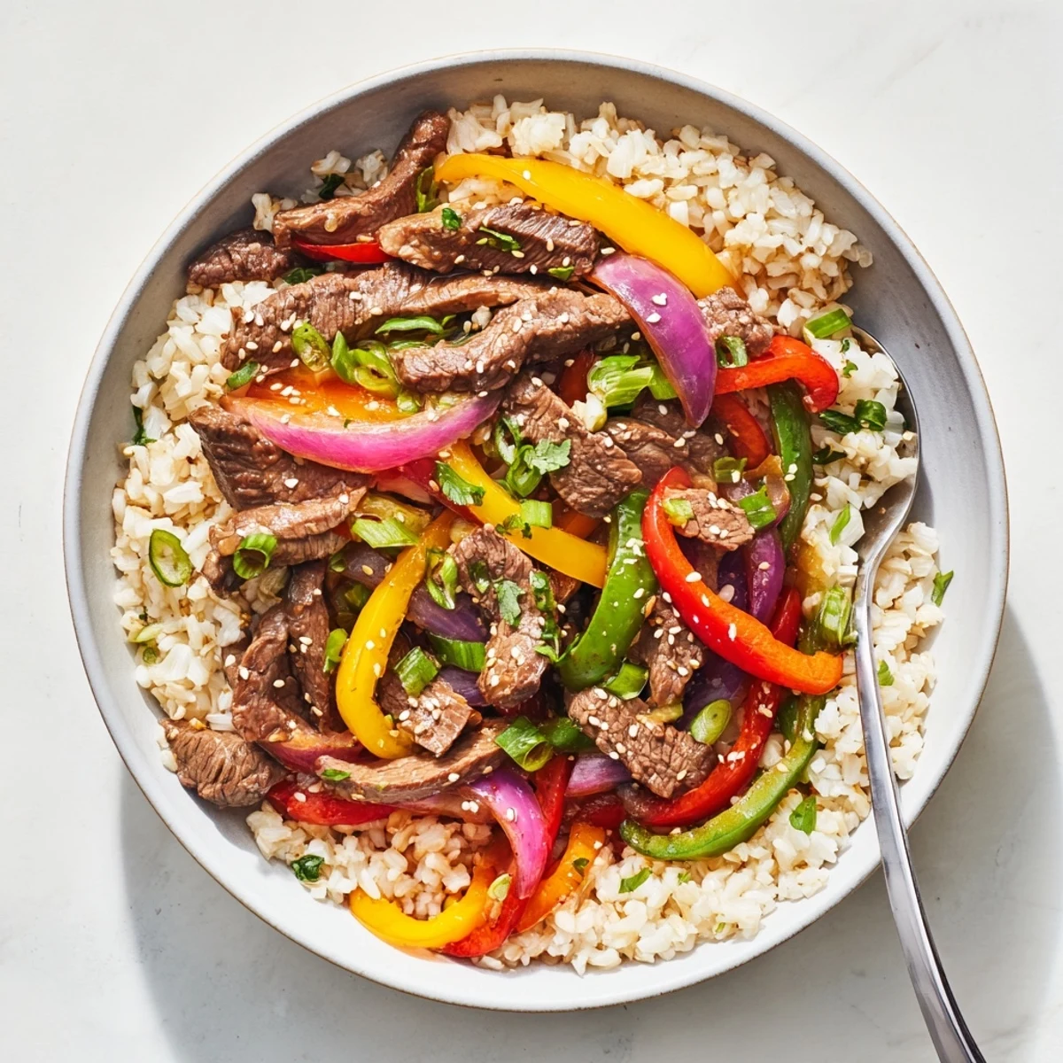 Vibrant healthy beef and pepper rice bowl showcasing red yellow and green peppers in a rich Asian-inspired sauce