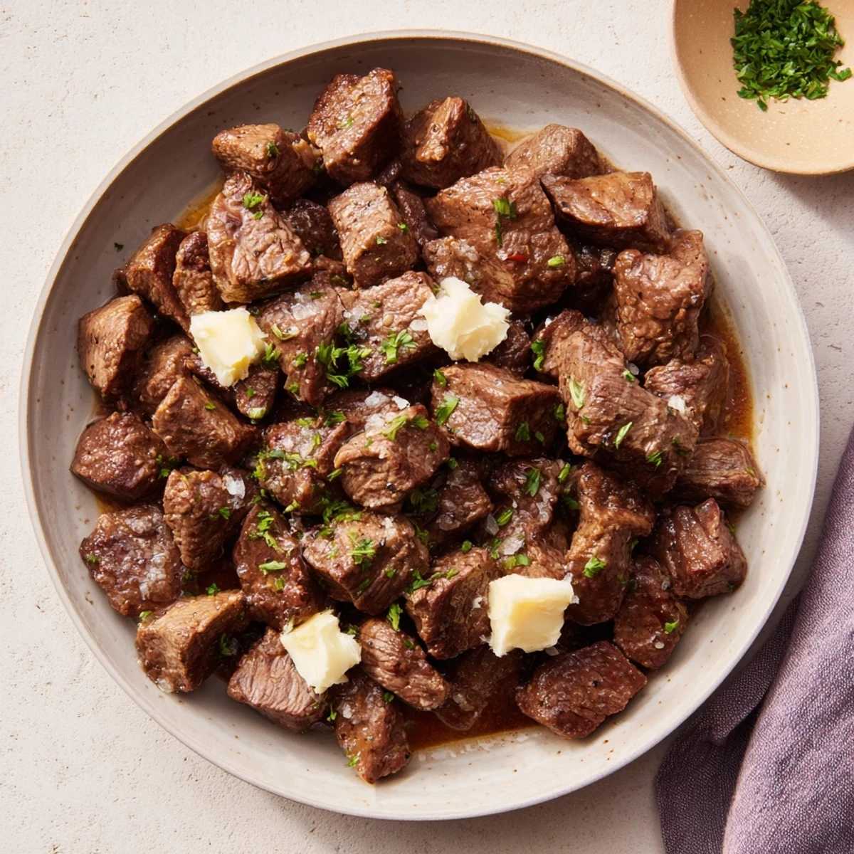 Tender crockpot steak bites simmered in garlic butter sauce with fresh parsley garnish