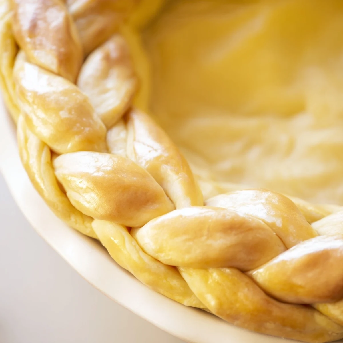 Golden brown fishtail braid pie crust with woven pastry edges ready for filling