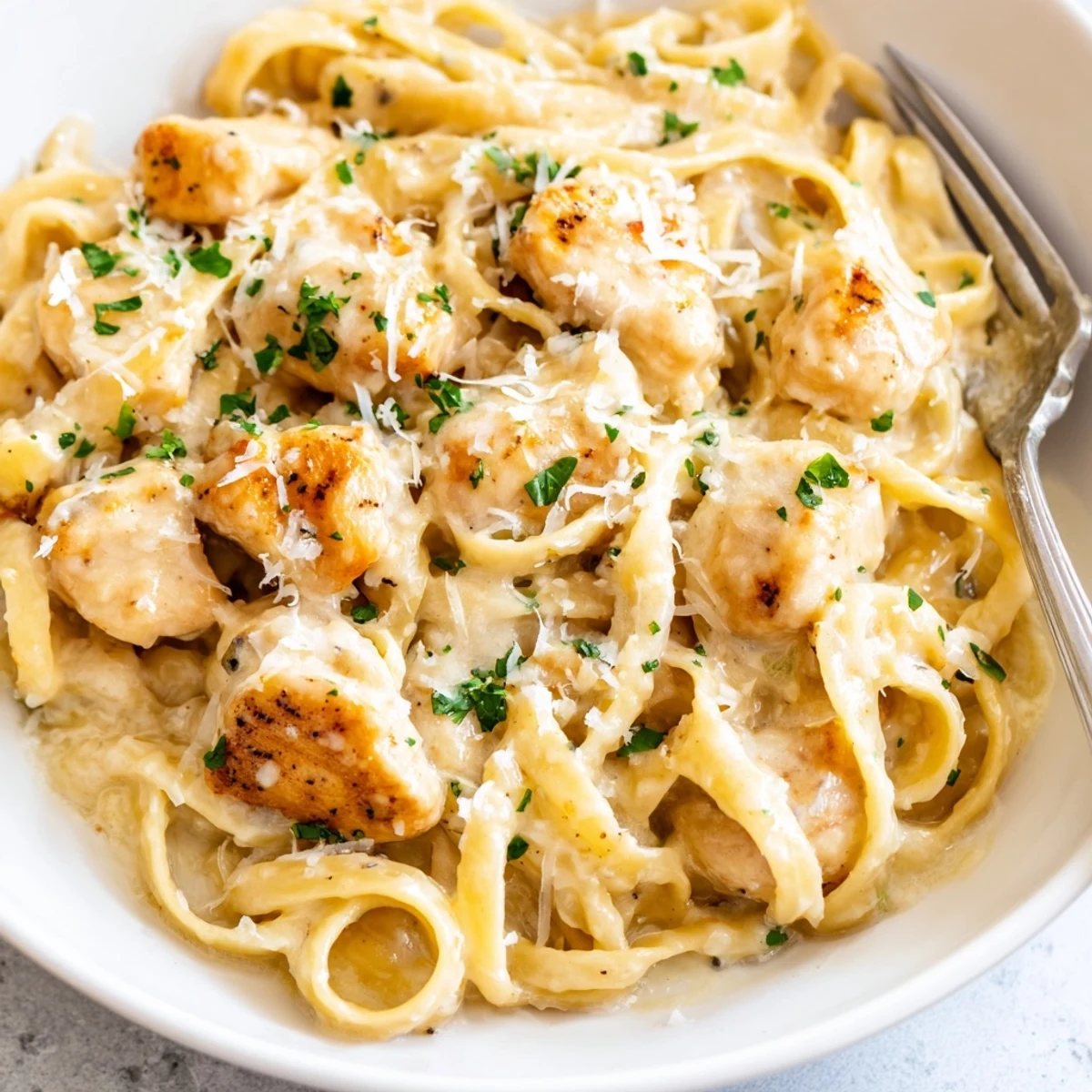 Golden brown chicken pieces mingled with fettuccine in a luscious white parmesan cream sauce