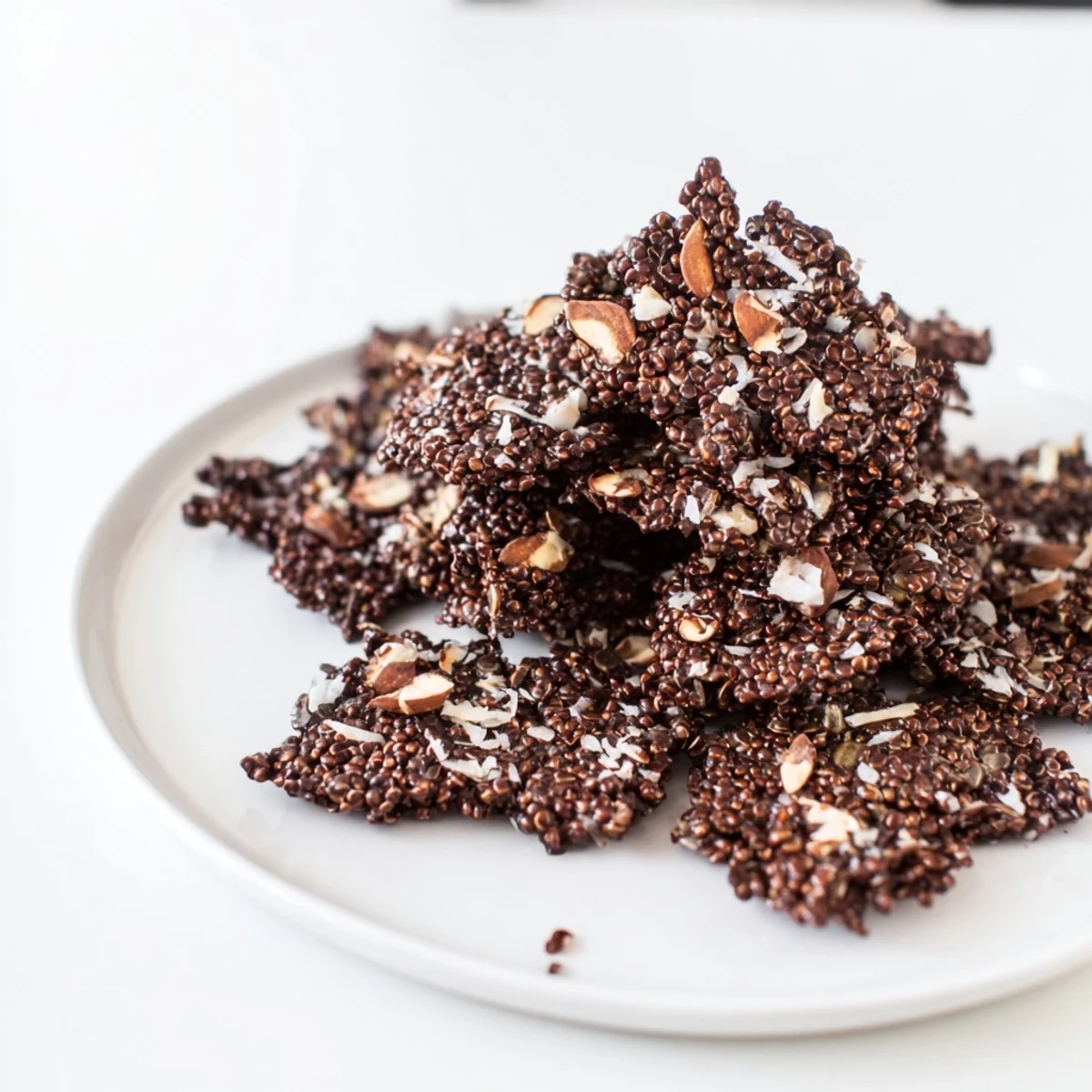 Homemade dark chocolate quinoa crisps topped with sea salt flakes cooling on parchment paper ready for gluten-free snacking
