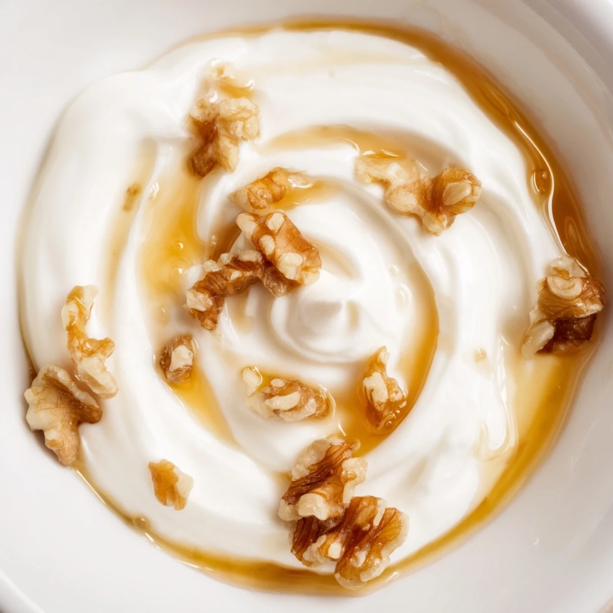 Thick Greek yogurt spoon showing rich texture drizzled with golden honey and crushed walnuts