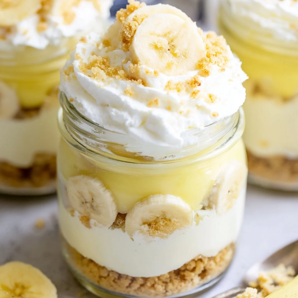 No bake banana pudding cheesecake cups topped with golden wafer crumbs and fresh banana slices