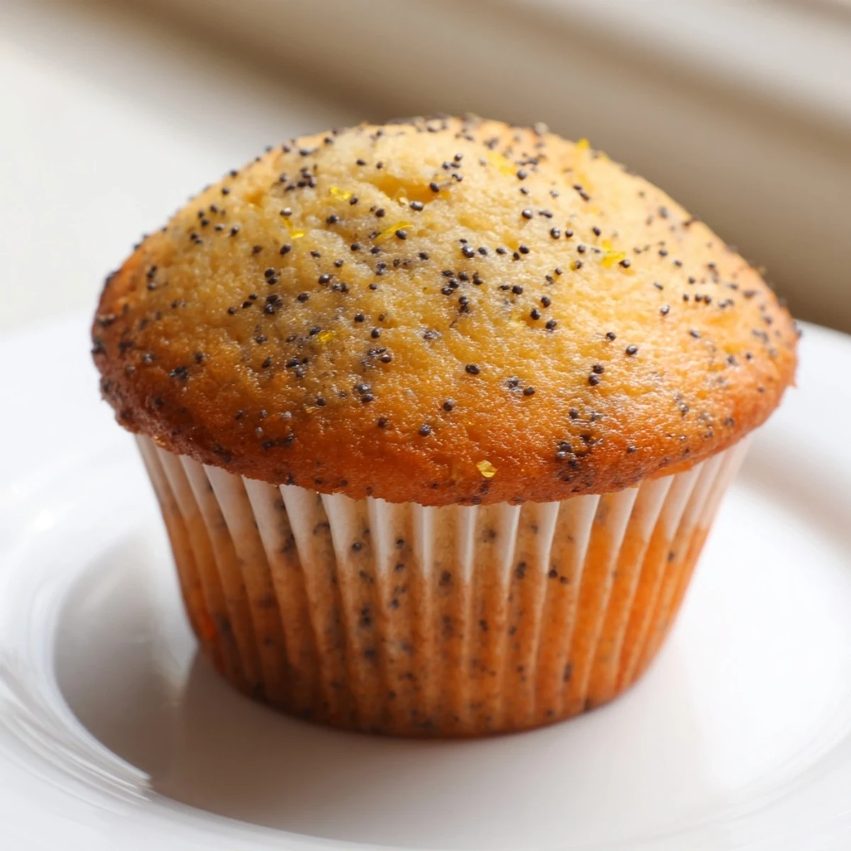 Moist Lemon Poppy Seed Muffins crowned with zest and served on a rustic ceramic plate.
