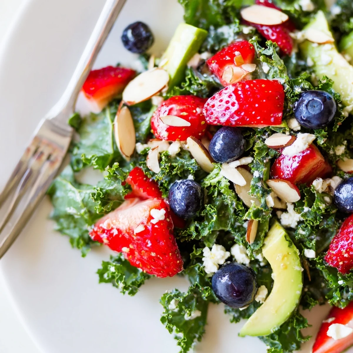 A colorful summer kale salad topped with fresh berries and toasted almonds