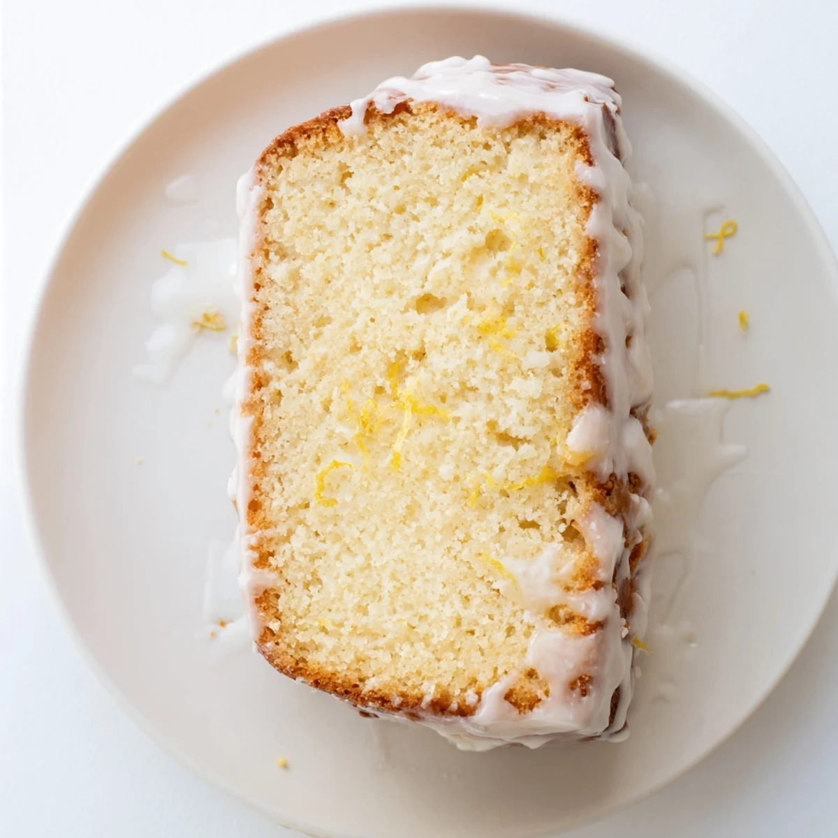 Golden Greek yogurt lemon loaf drizzled with white lemon glaze on a wooden board