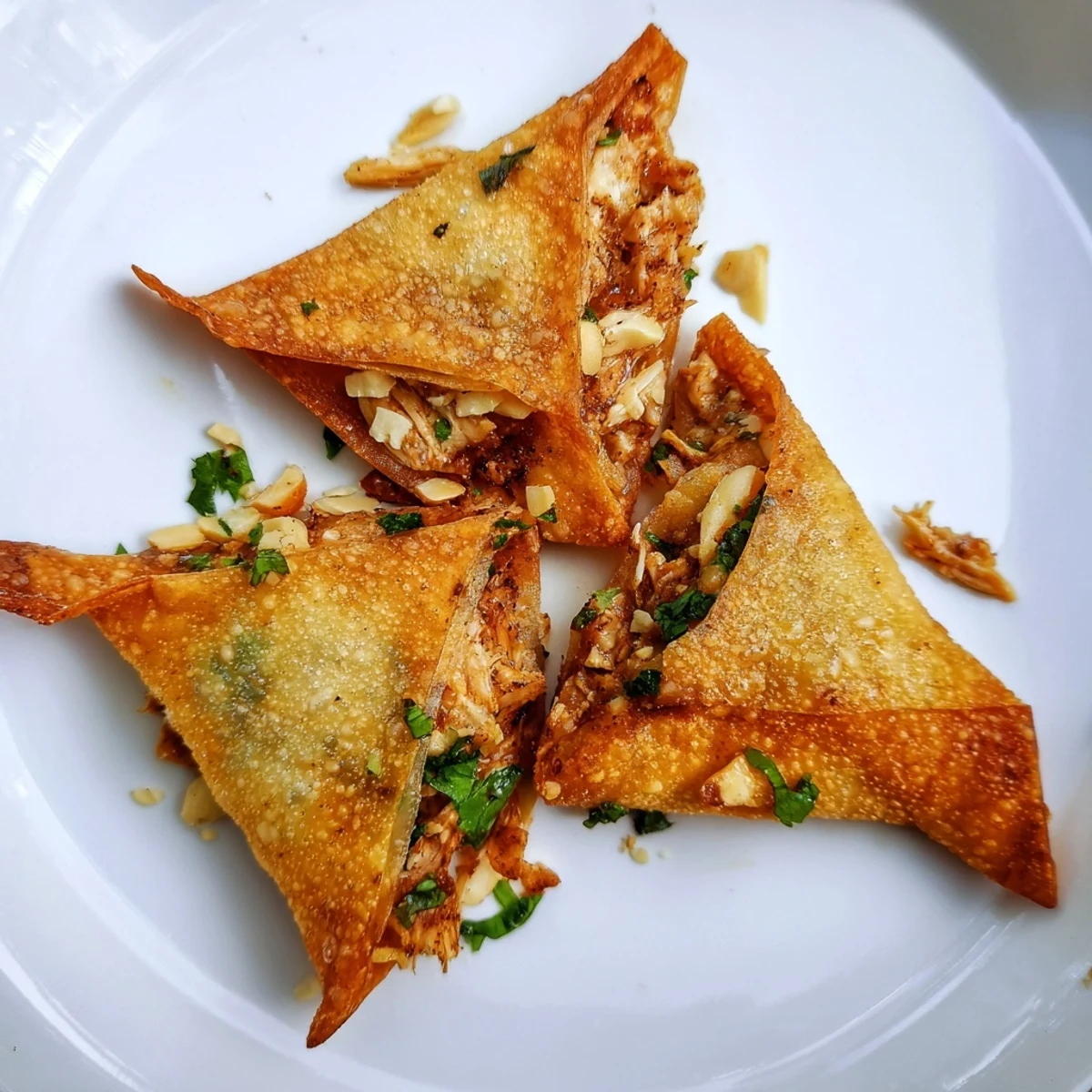 Deep-fried triangle pastry filled with spiced chicken and almonds glistening with oil