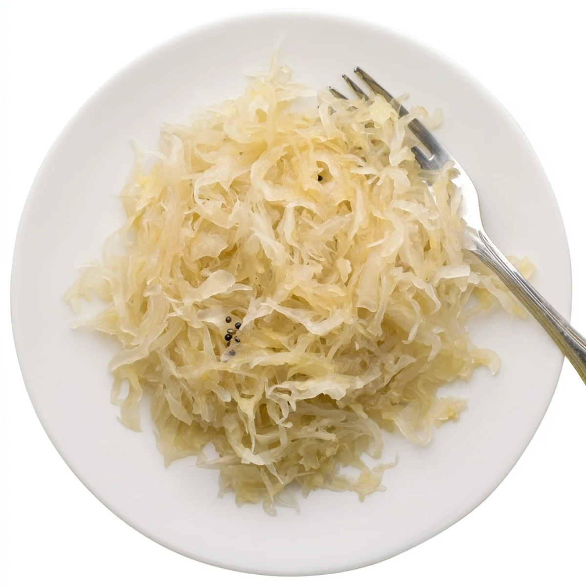 Golden fermented sauerkraut in a glass jar with wisps of shredded cabbage visible