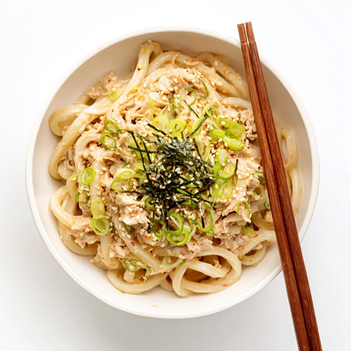 Thick chewy udon noodles tossed in creamy spicy tuna sauce with green onion toppings