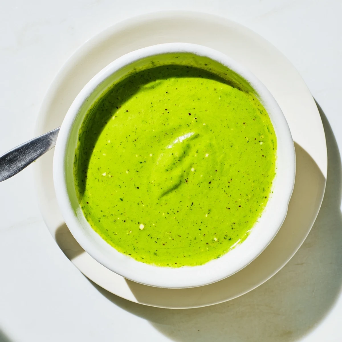 Vibrant bowl of Peruvian green sauce aji verde ready for dipping with tortilla chips