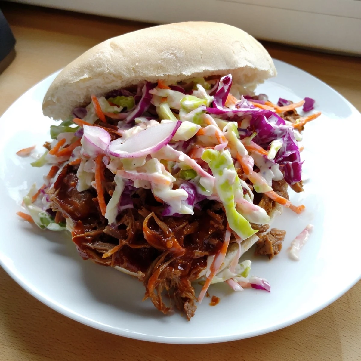 Golden smoky BBQ beef sandwich piled high with crisp colorful coleslaw on toasted bun