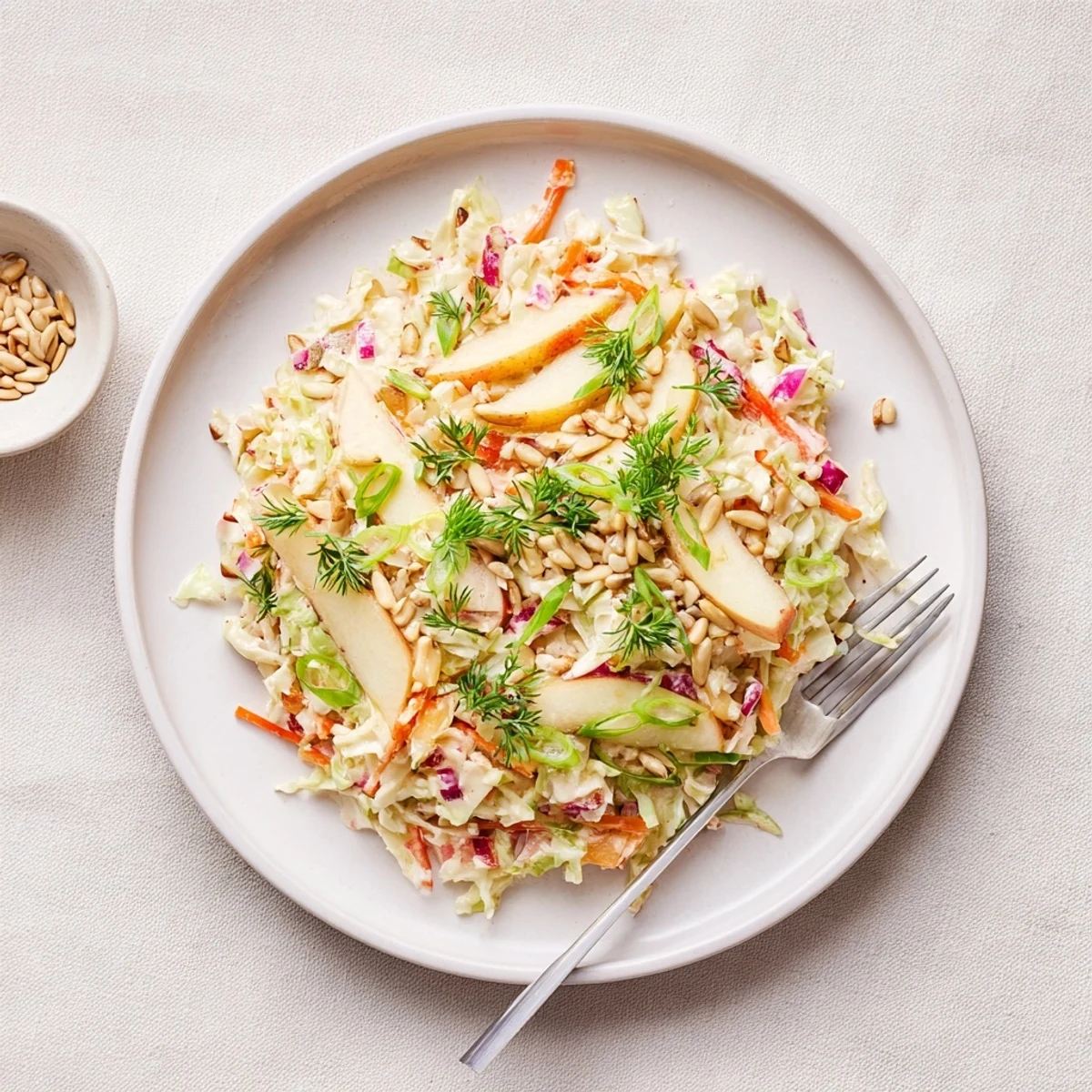 Colorful apple coleslaw mixture in glass bowl with tangy honey dressing coating crunchy cabbage and apples