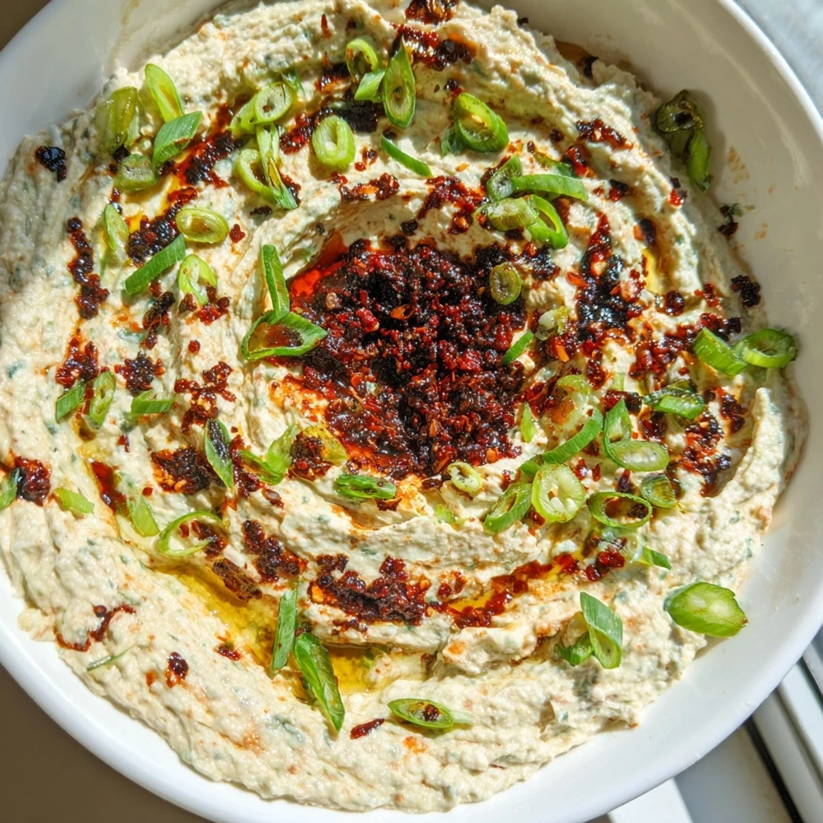 Creamy charred scallion and chili crisp dip topped with a spicy swirl