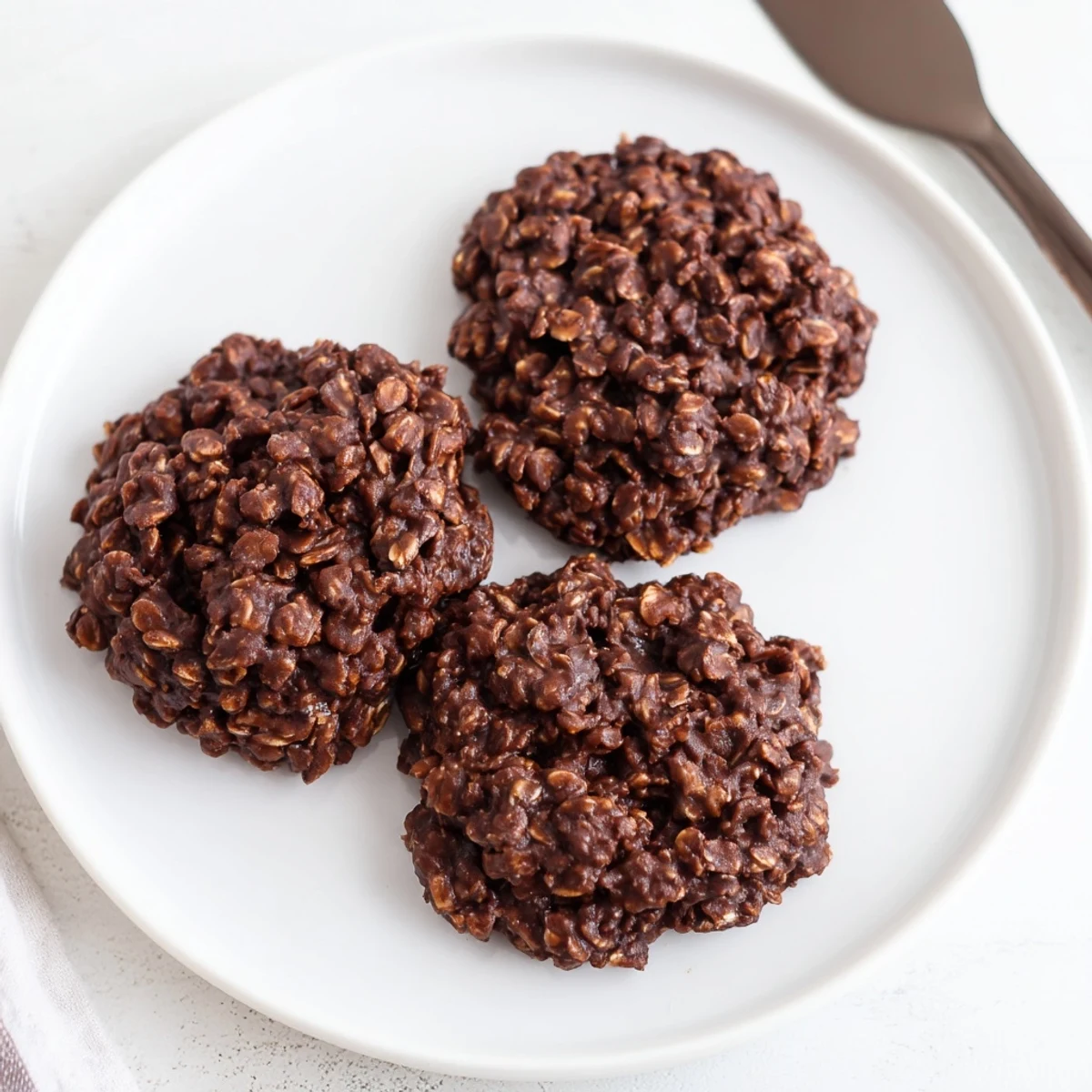 Fudgy chocolate oatmeal no bake cookies piled on parchment paper with rich cocoa sheen