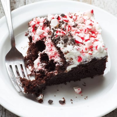 Slice of Peppermint Poke Cake showing pudding-filled holes and minty aroma.
